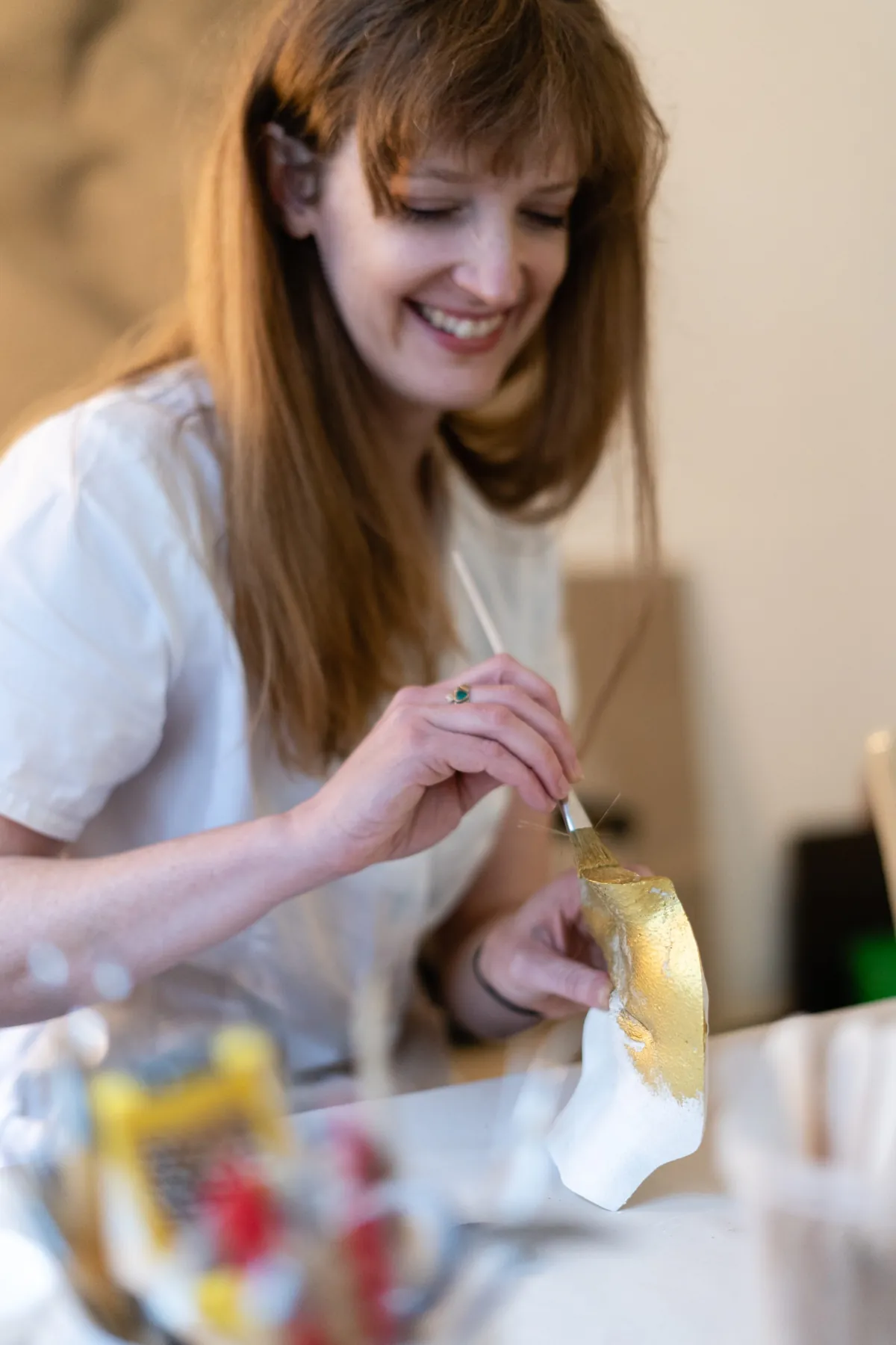 Brooke trägt mit einem feinen Pinsel Blattgold auf einen Gipsabguss auf