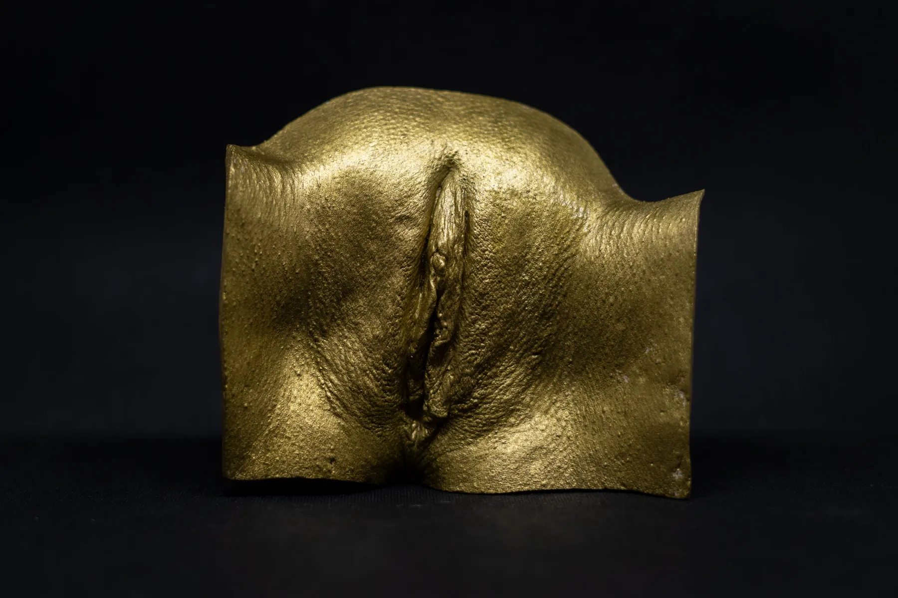 Vulva-Abformung mit Blattgold auf Schwarz