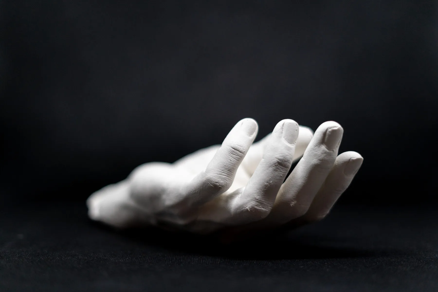 Gipsabguss einer Hand, die mit der Handfläche nach unten auf Schwarz ruht