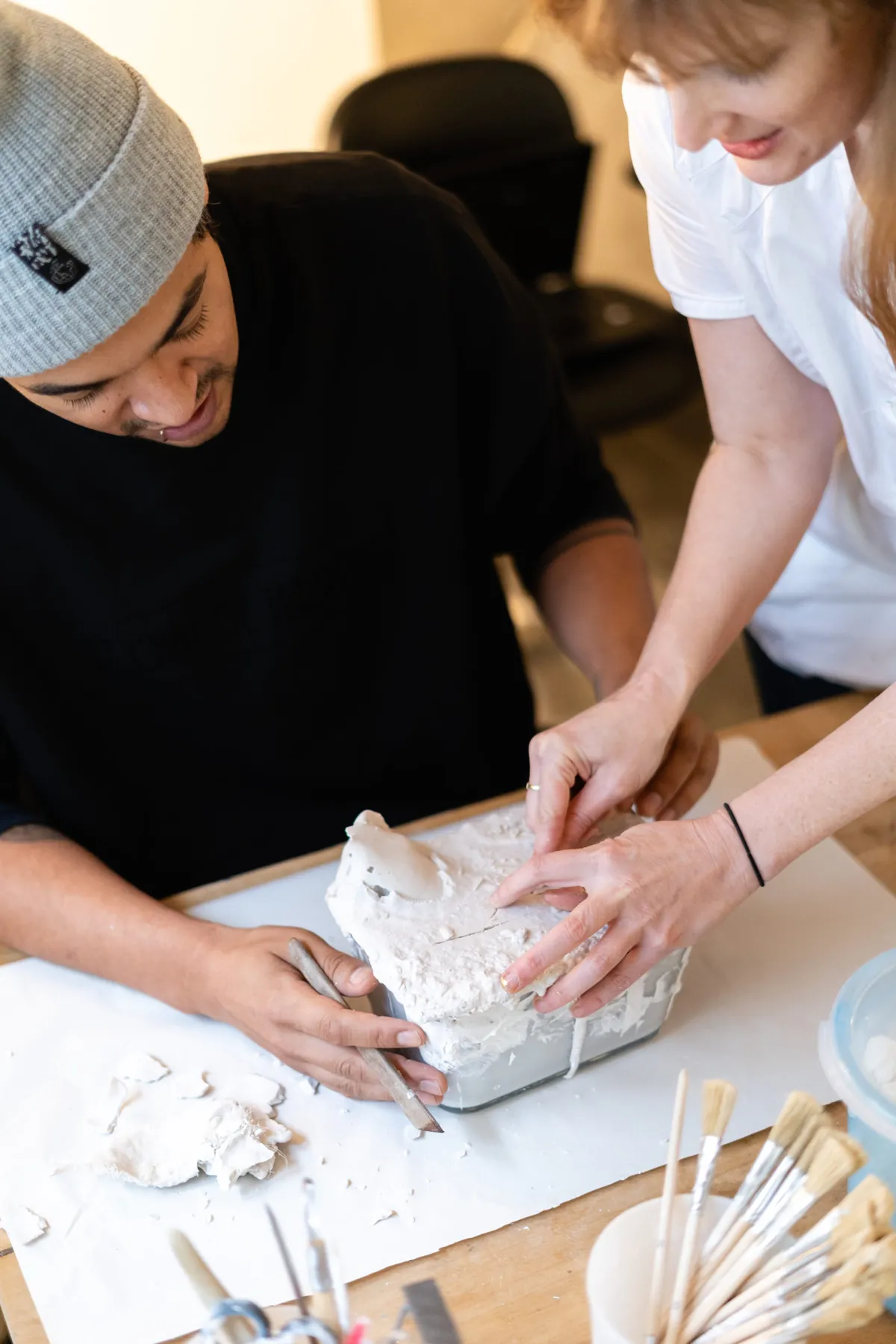 Brooke helping a participant free a plaster cast from its mould