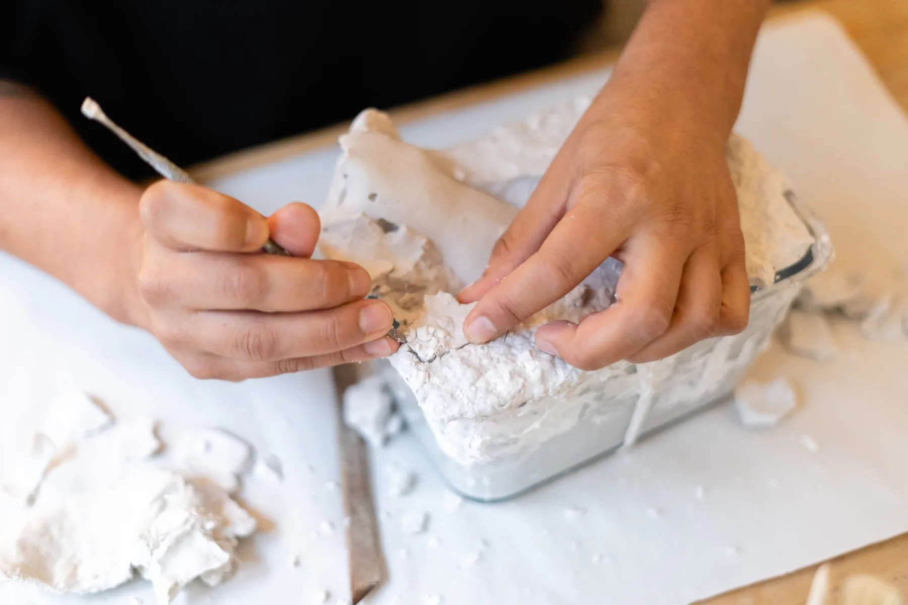Hände lösen während eines Workshops behutsam einen Gipsabguss aus seiner Form